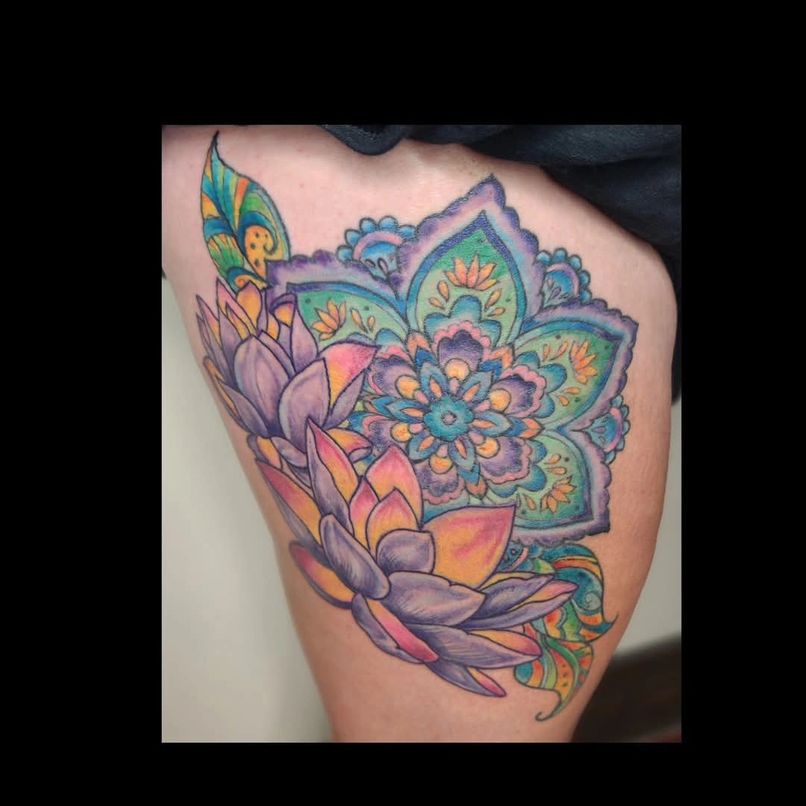 Colorful floral tattoo with lotus flowers and mandala patterns on skin, vibrant and detailed design.