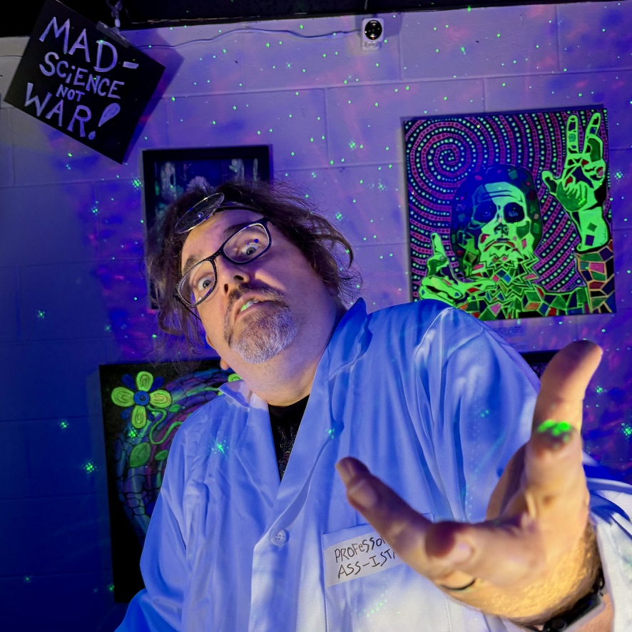 Person with glasses in a lab coat reaching out, surrounded by colorful psychedelic artwork and a sign that says 'MAD SCIENCE NOT WAR!'.