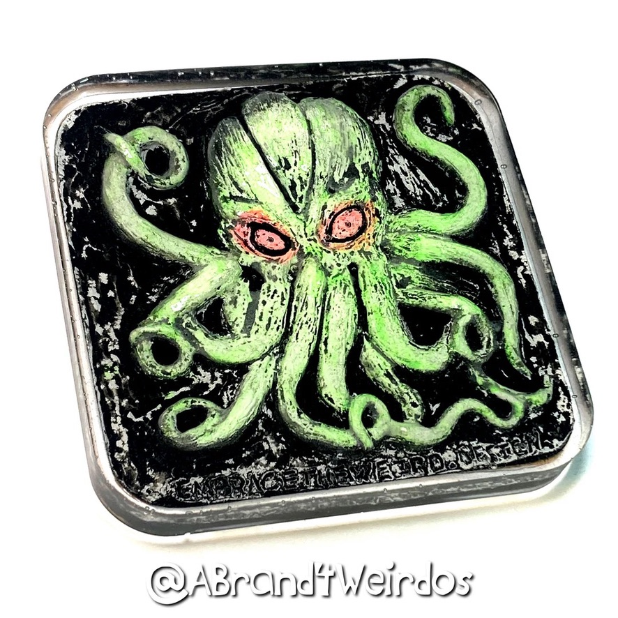 Square object with a green octopus illustration on a black background, with pink eyes and tentacles extending outward.
