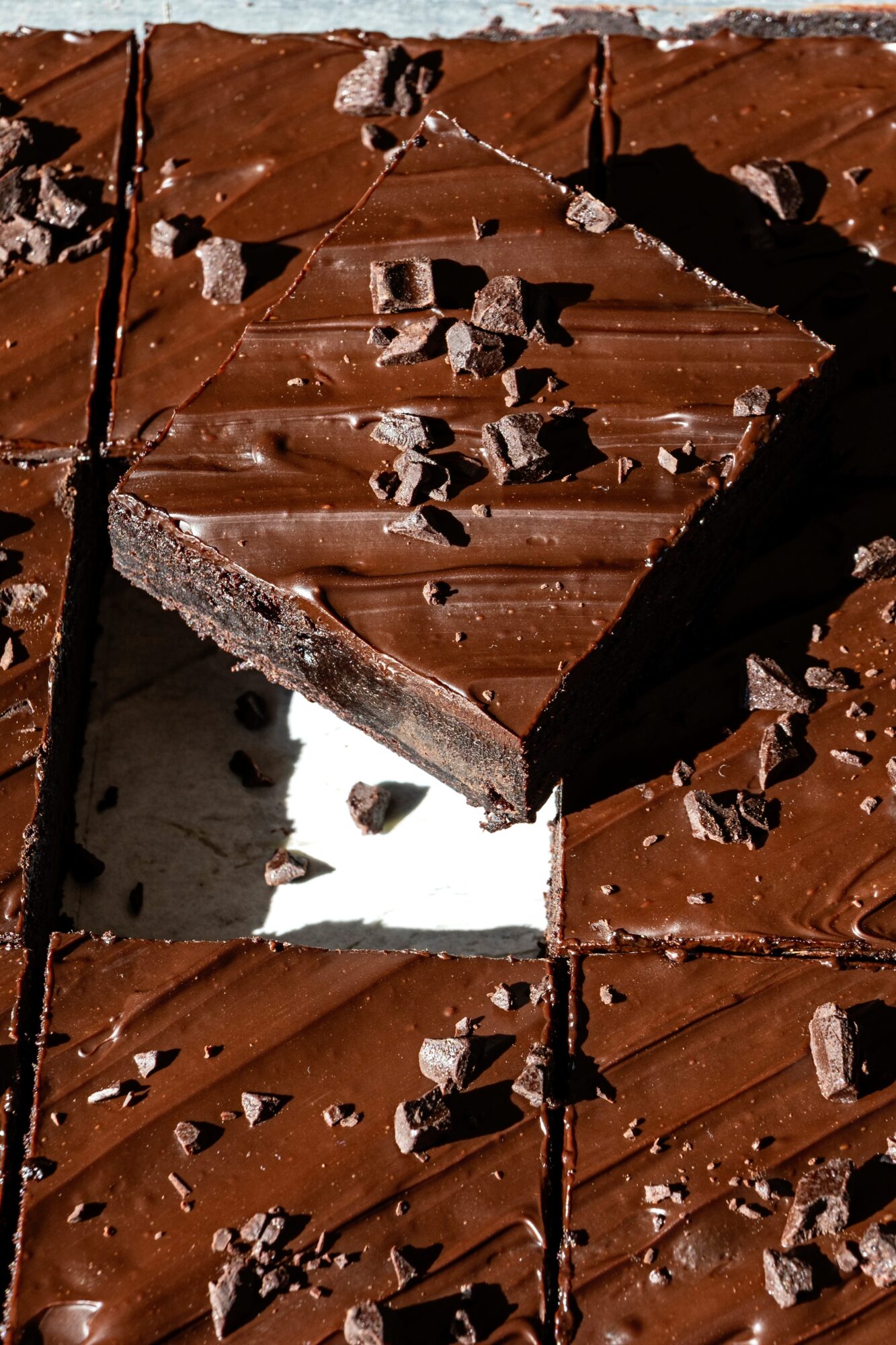 Broken chocolate bar with pieces and crumbs, some broken off, on a dark surface.