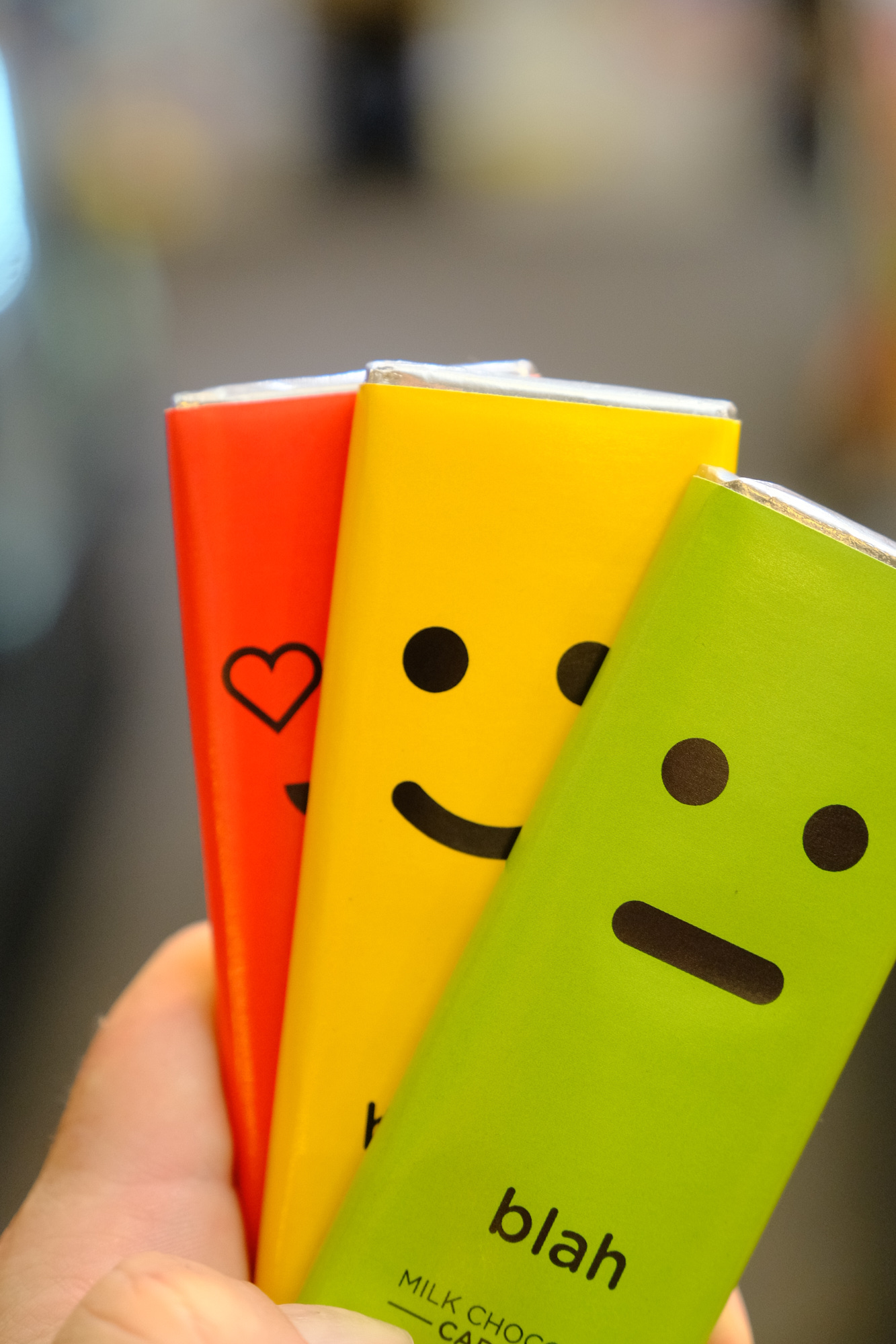 Person holding three colorful notebooks with smiley faces and text, blurred background.