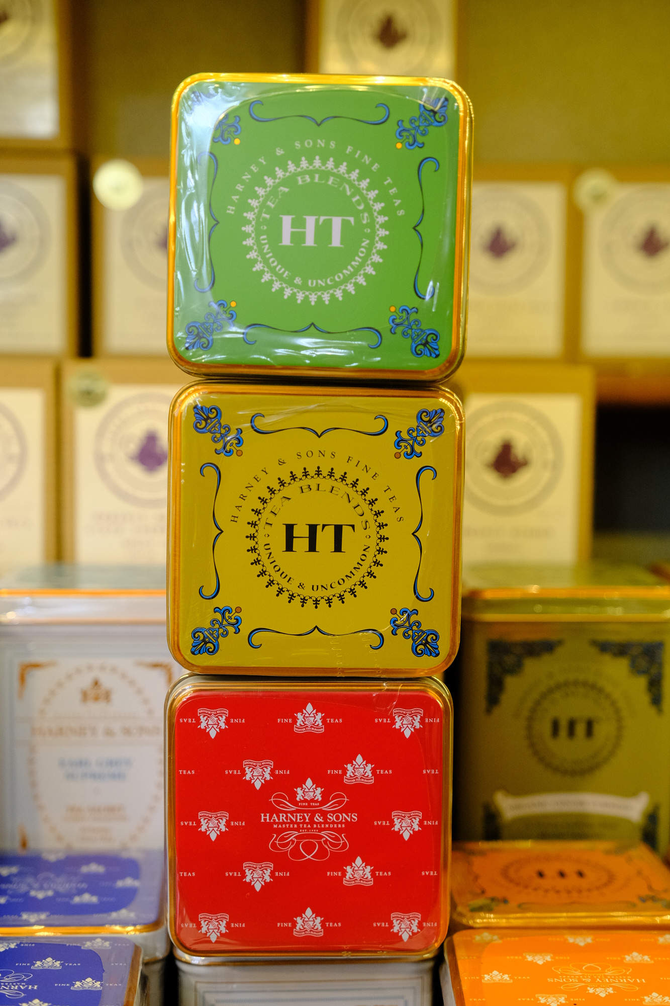 Three colorful boxes stacked vertically with decorative patterns and the letters 'HT' on each, in a store setting.