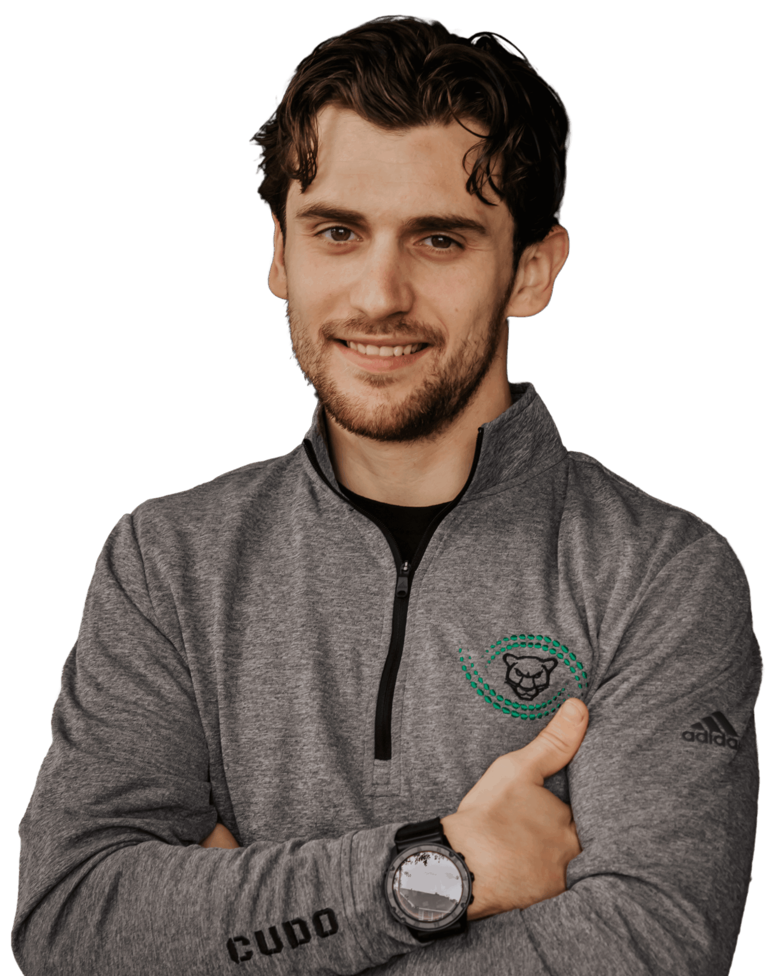 Young man with dark hair and beard, smiling, wearing a gray zip-up jacket and a watch, against a black background.