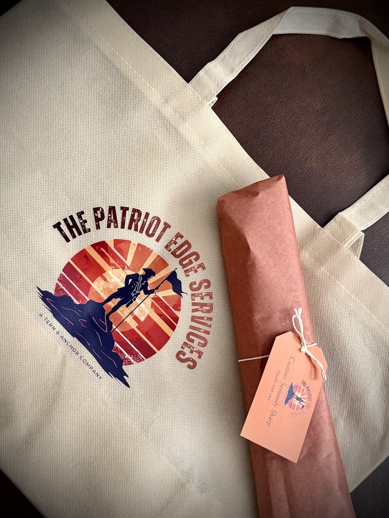 A beige tote bag with a patriotic logo featuring a person running, a sunburst background, and text, with a pink wrapped item and tag.