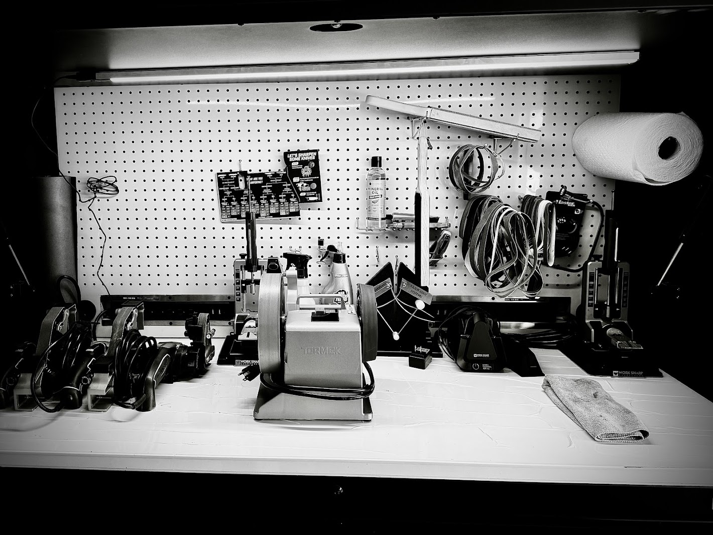 Workstation with tools, cables, and equipment organized on a pegboard and surface, in black and white.