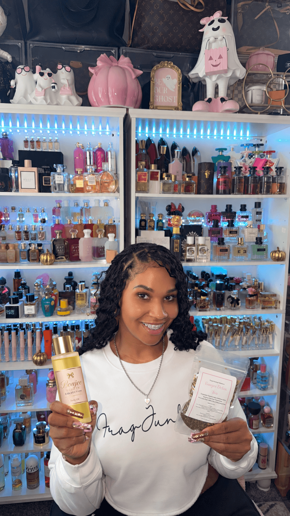 Smiling woman holding a yellow bottle and a white box in a store with shelves of beauty products behind her.