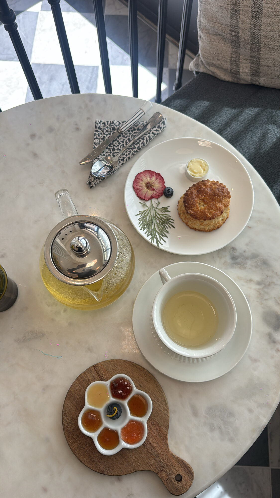 Table with a plate of food, a teapot, a cup of tea, and a honeycomb on a wooden board.