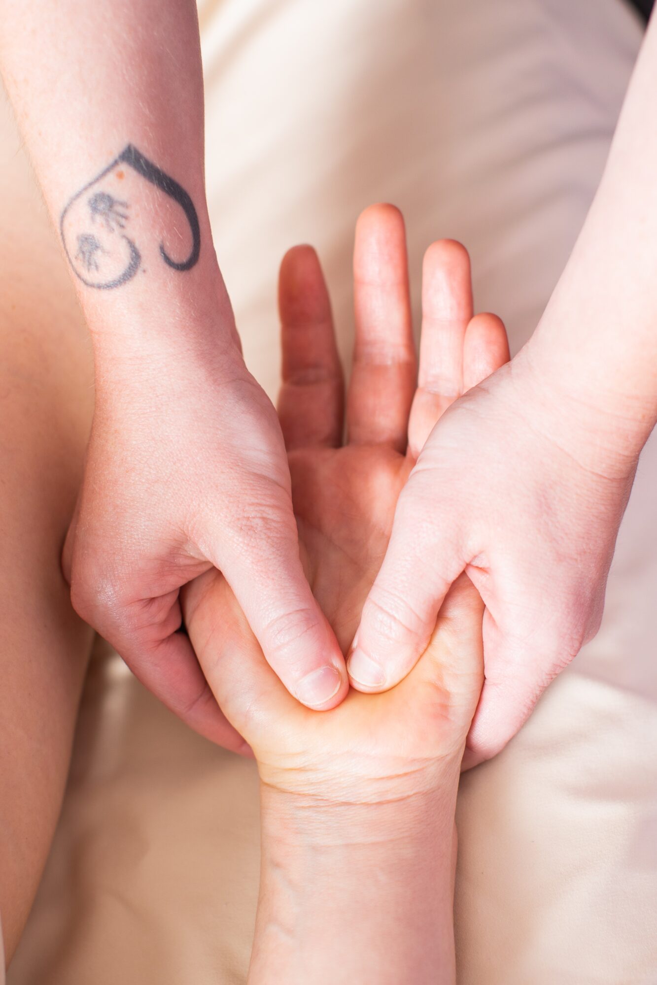 Two hands holding a child's hand, one with a tattoo of a bicycle, in a close-up shot.
