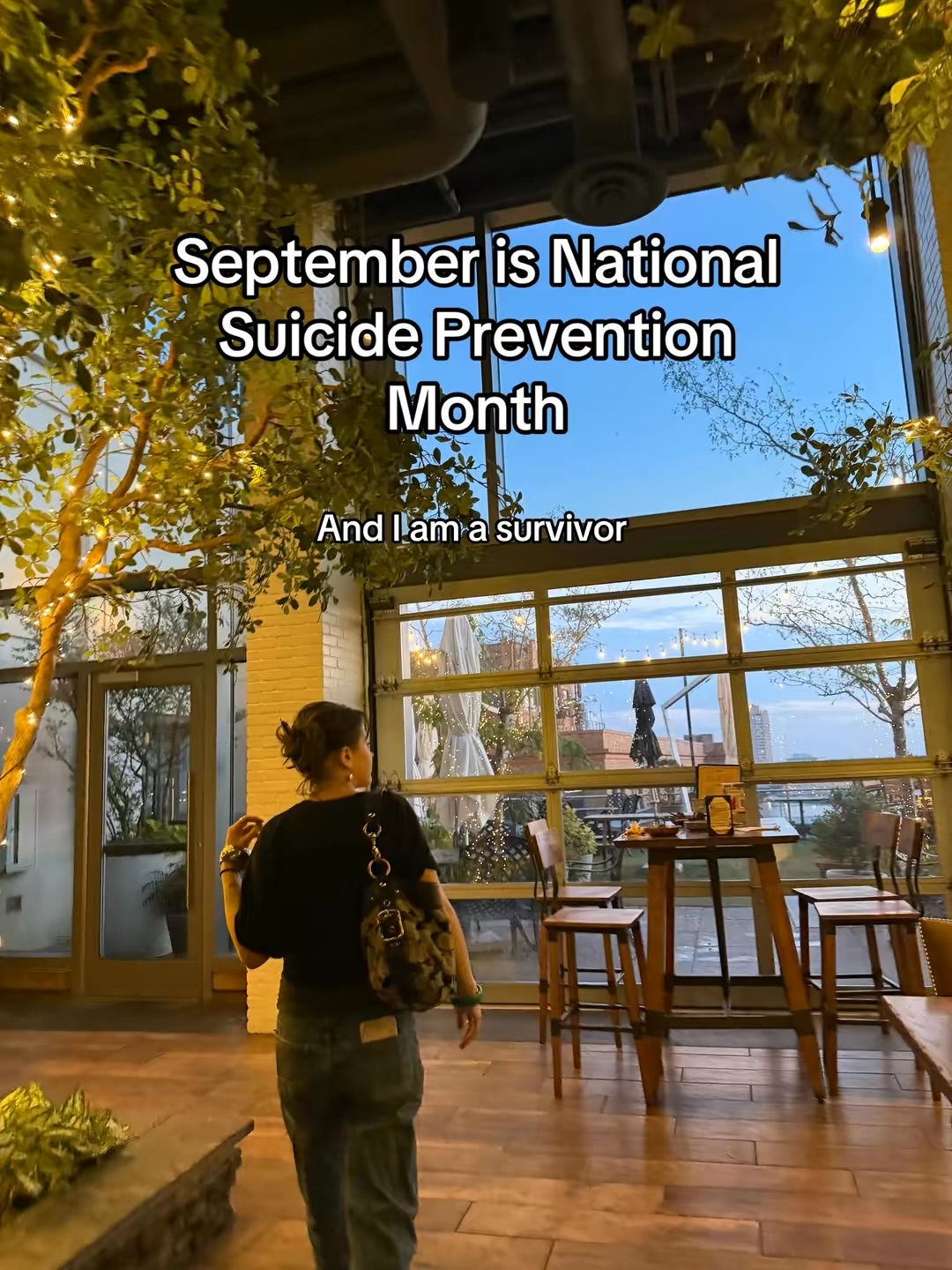 Person standing indoors near large windows with trees outside, text about September as National Suicide Prevention Month, 20 words.