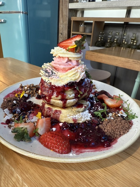 Dessert with layered cake, strawberries, and various toppings on a white plate, on a wooden table.