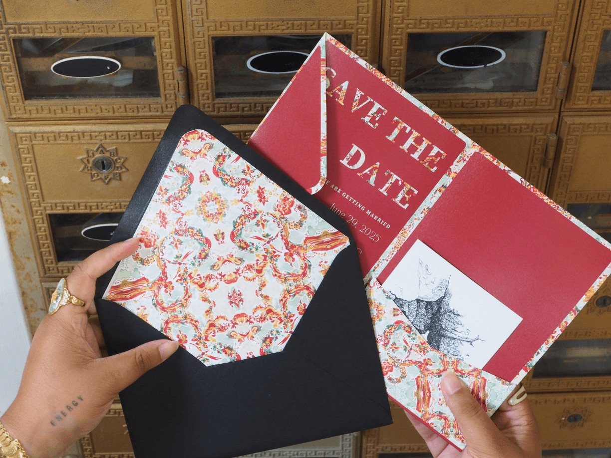 Person holding a black envelope with a patterned card inside, and two red and white cards with text and images behind.