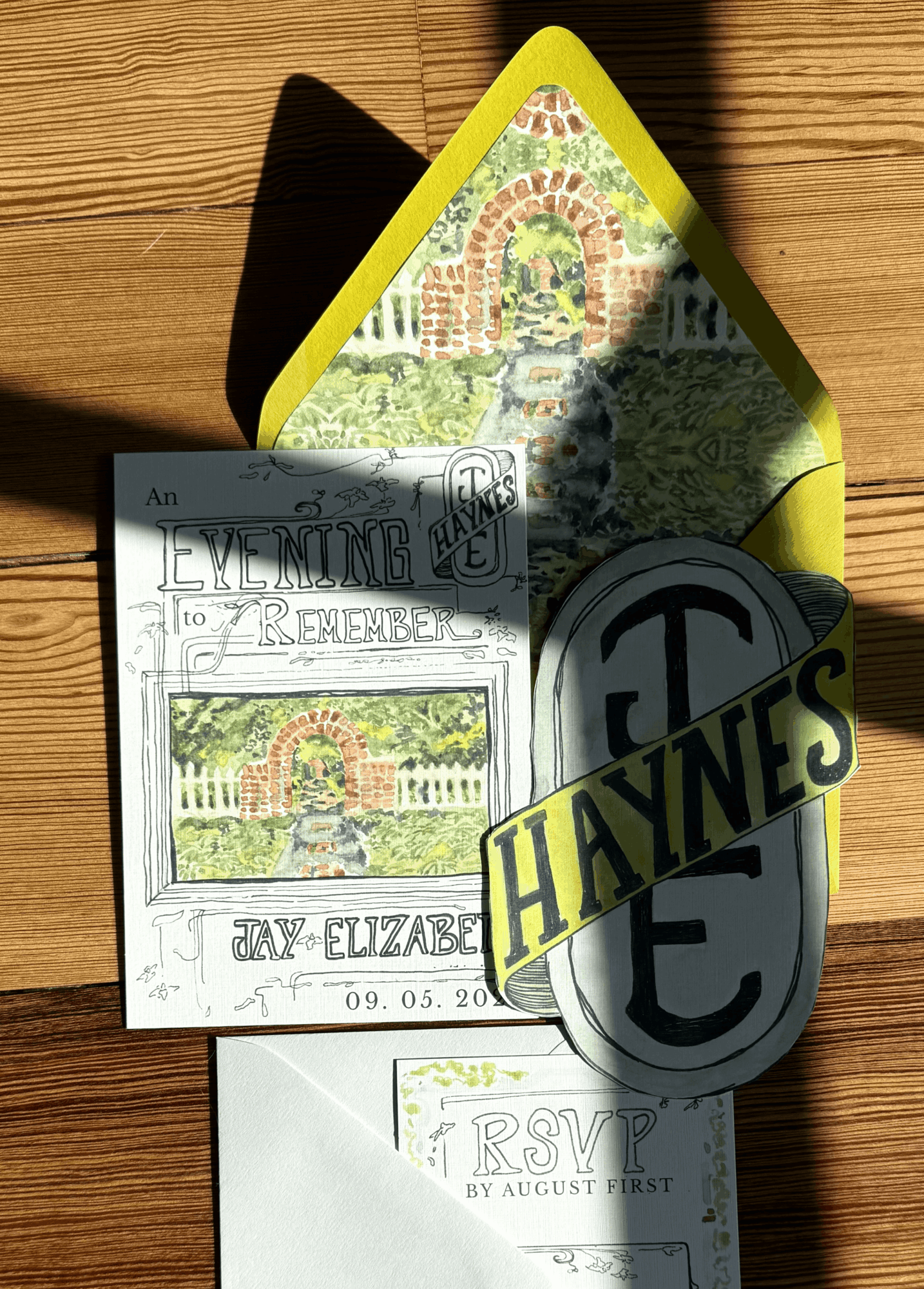 Colorful card with rainbow and brick design, shadow cast on wooden surface, partially covering a black and yellow object, and a white paper with text.