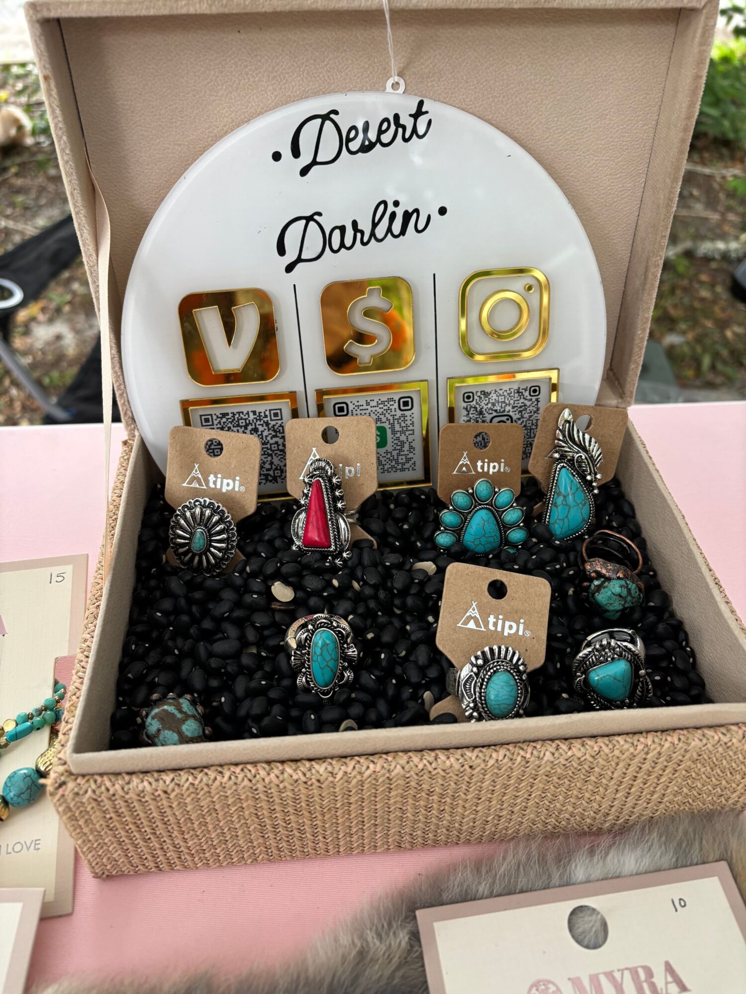 Open jewelry box with a white dish, assorted earrings, and black beads.