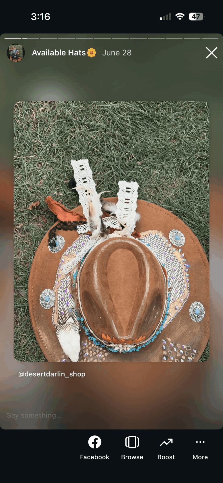 Social media story showing a decorated brown hat on grass, with small white accessories and a date at the top.