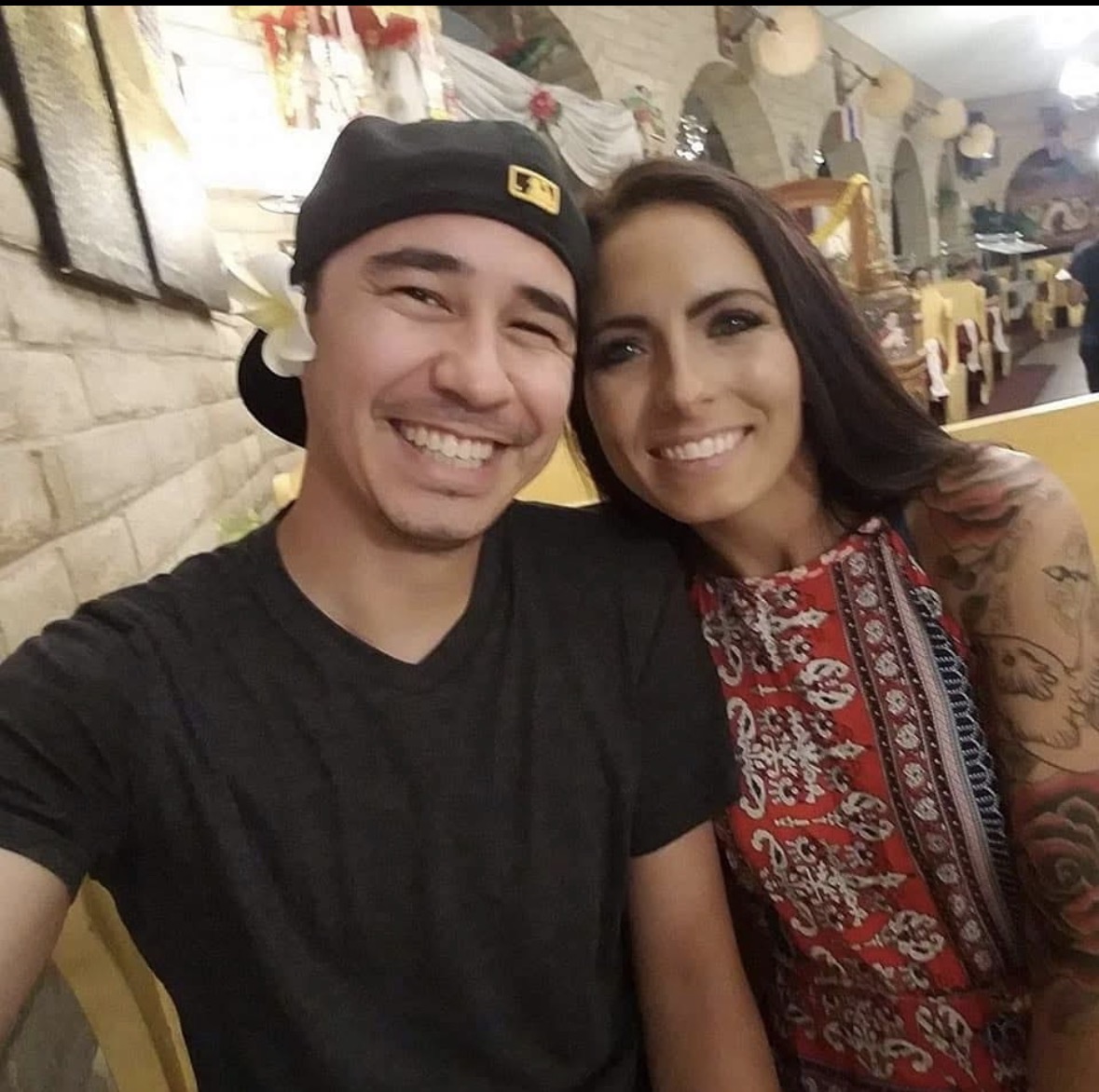 Two people smiling for a selfie in a decorated indoor space.