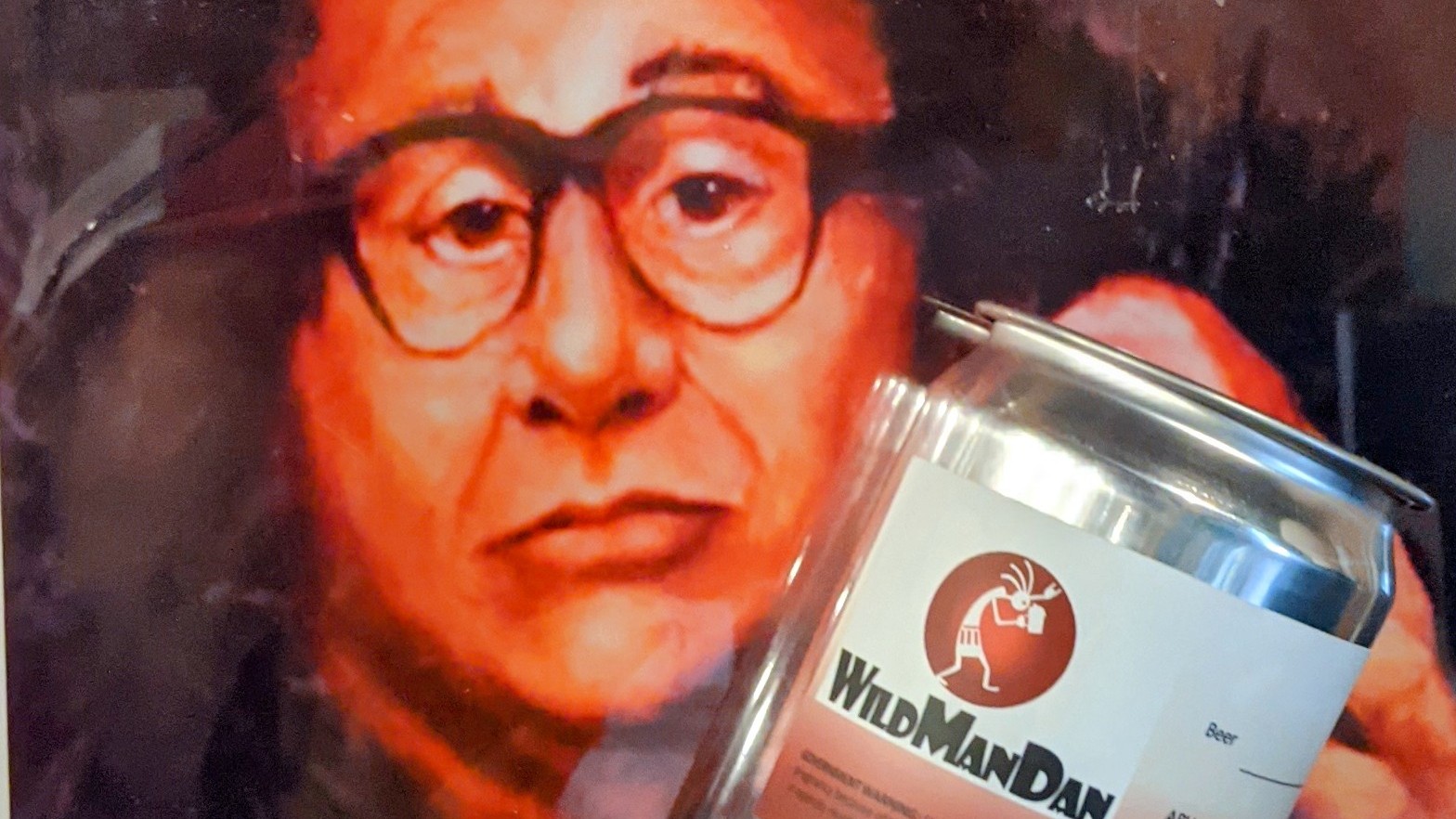 Person with glasses holding a can with a label that reads 'WorldLand'.
