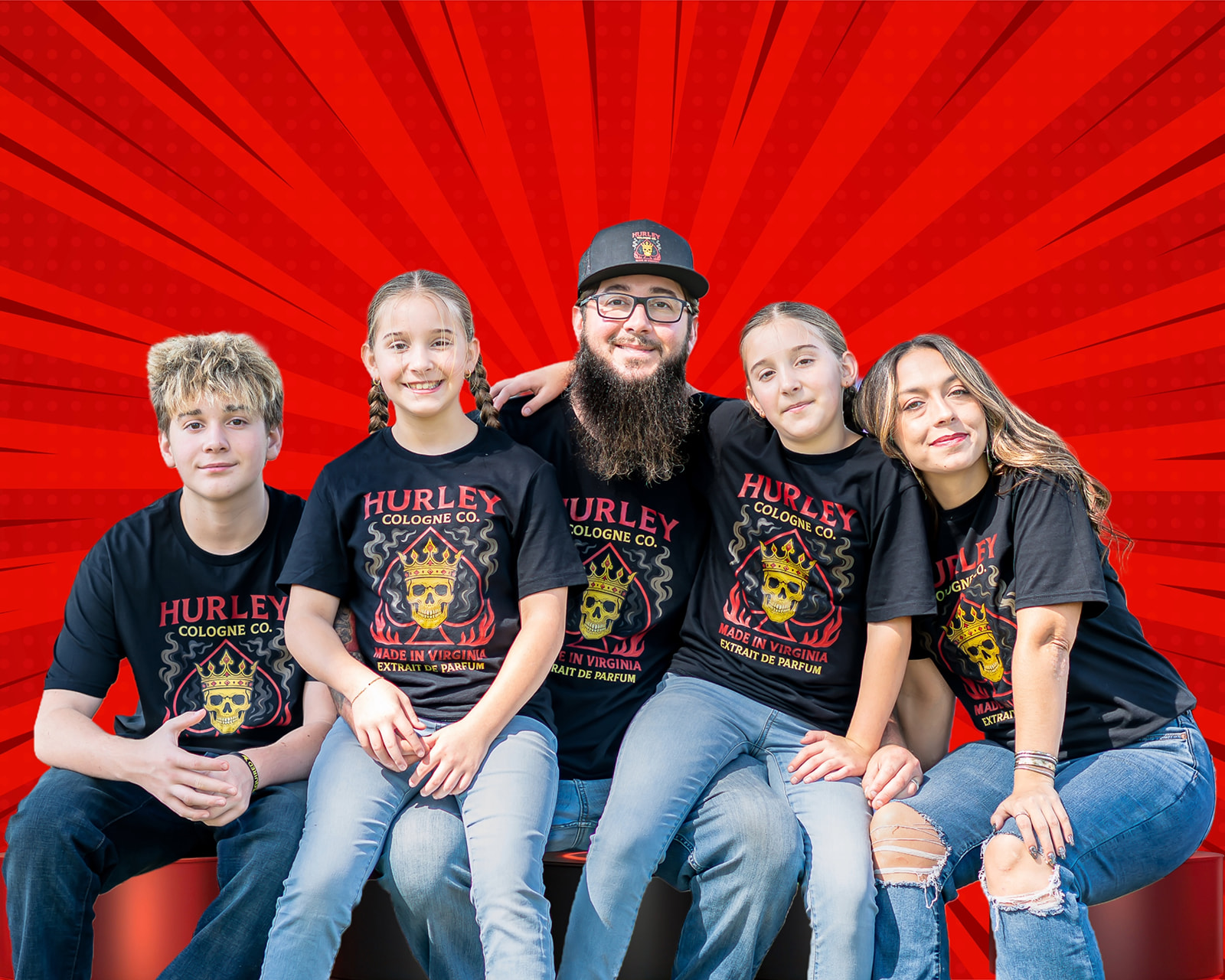 Group of four people sitting together, smiling, wearing black Hurley College of Music T-shirts, against a red background with rays.