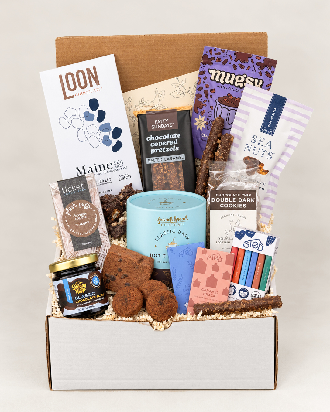 Open box with assorted snacks, chocolates, and a blue container, arranged with various packaging visible.