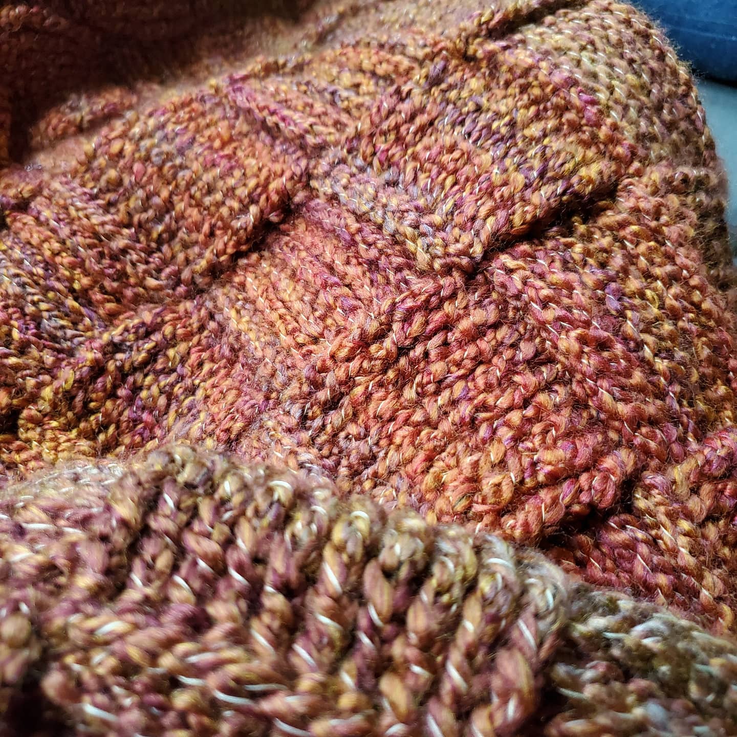 Close-up of multicolored, textured knitted fabric with various stitch patterns and yarns.