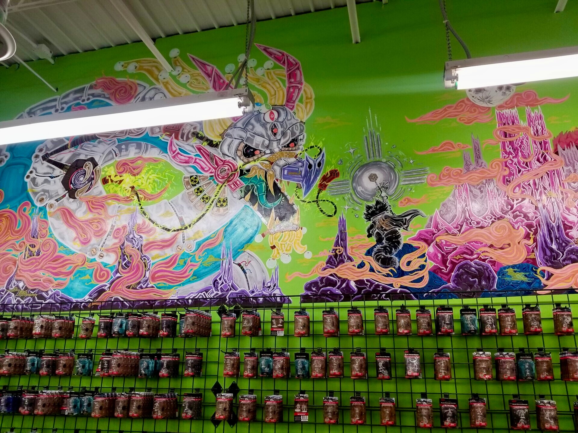 Colorful mural with abstract and fantastical elements on a green wall, above a row of pink and black vending machines.