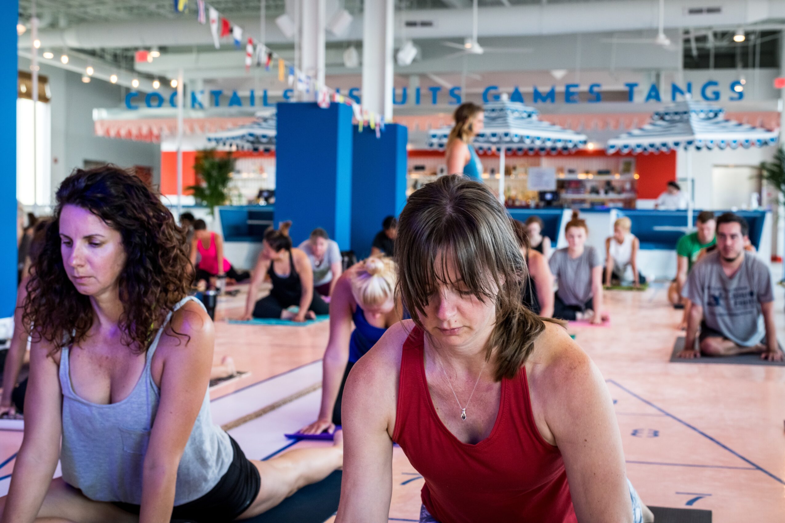 People sitting on the floor at an indoor skating rink with a sign reading 'GAMES TANGS' in the background.