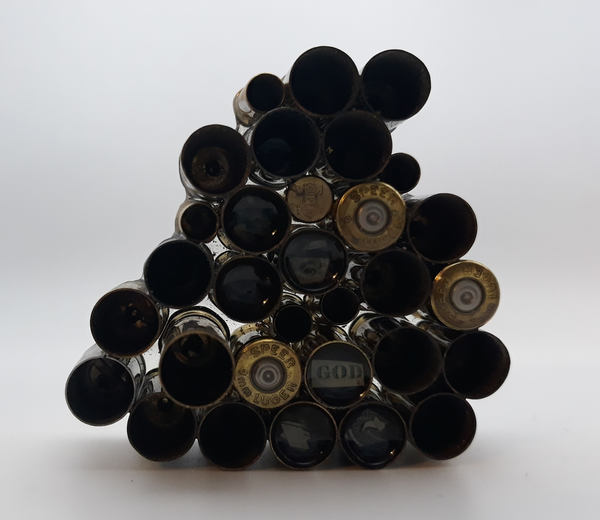 A pyramid-shaped arrangement of wine bottles viewed from the bottom, with the open ends facing upward, against a plain background.