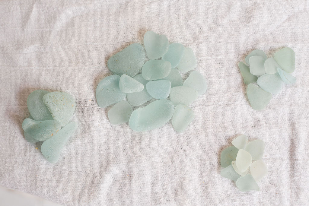 Small clusters of light green, blue, and white heart-shaped stones on fabric surface.