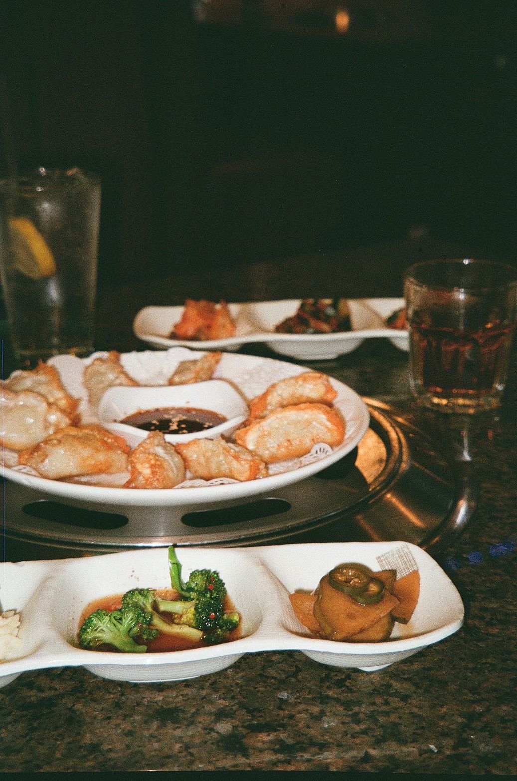 Plates of shrimp, dipping sauce, and vegetables on a restaurant table with drinks.