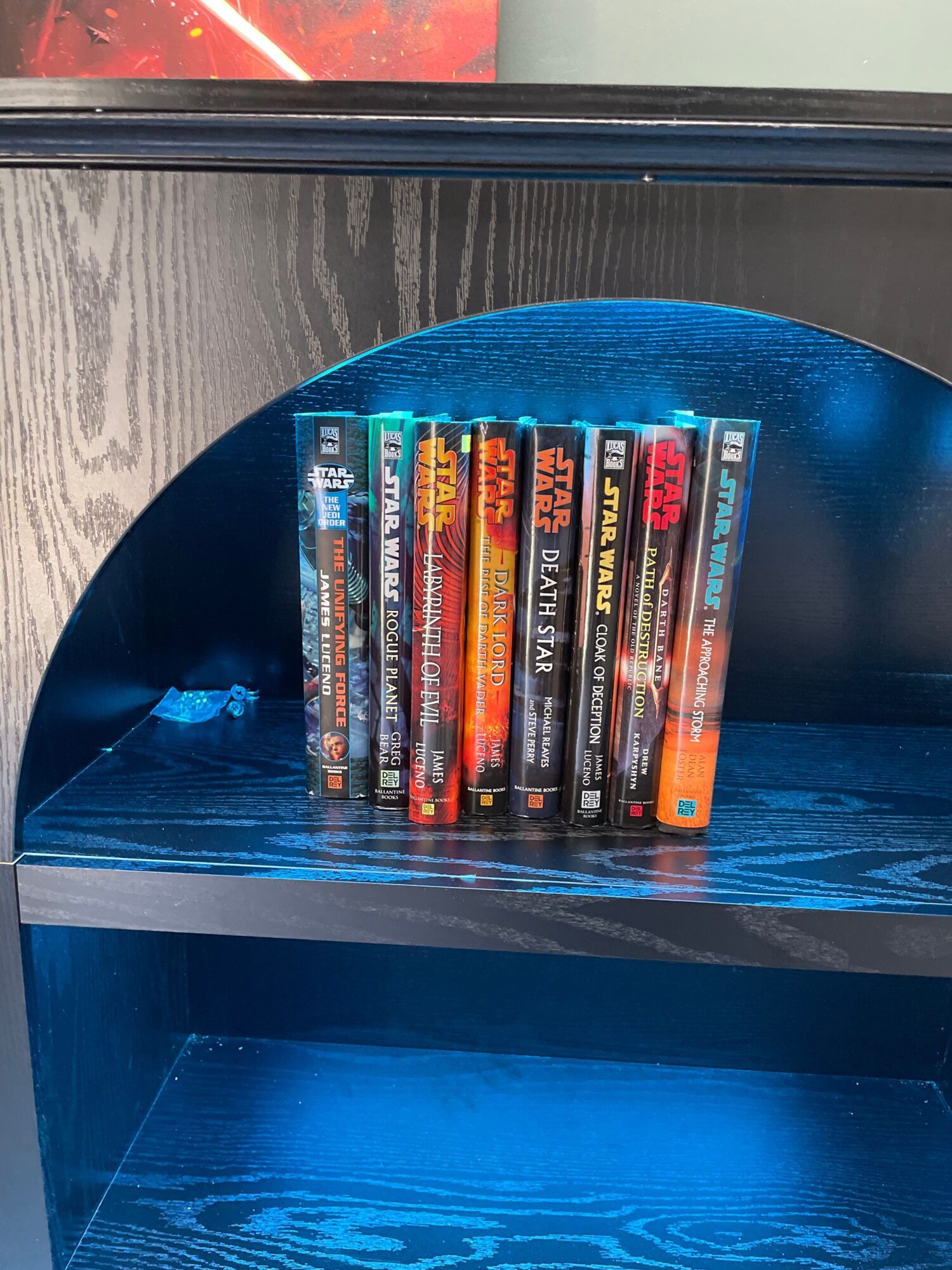 A stack of Star Wars movie cases sits on a shelf inside a blue-lit display cabinet.