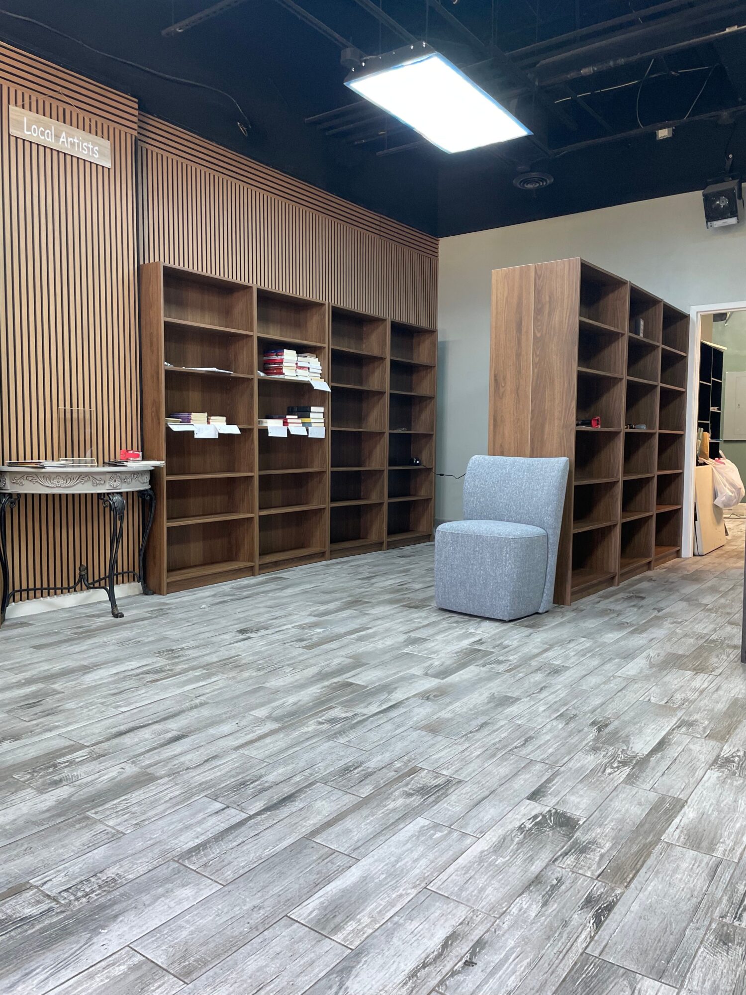 Wooden shelving and slatted panels in a tiled interior, with a small lit display on the left.