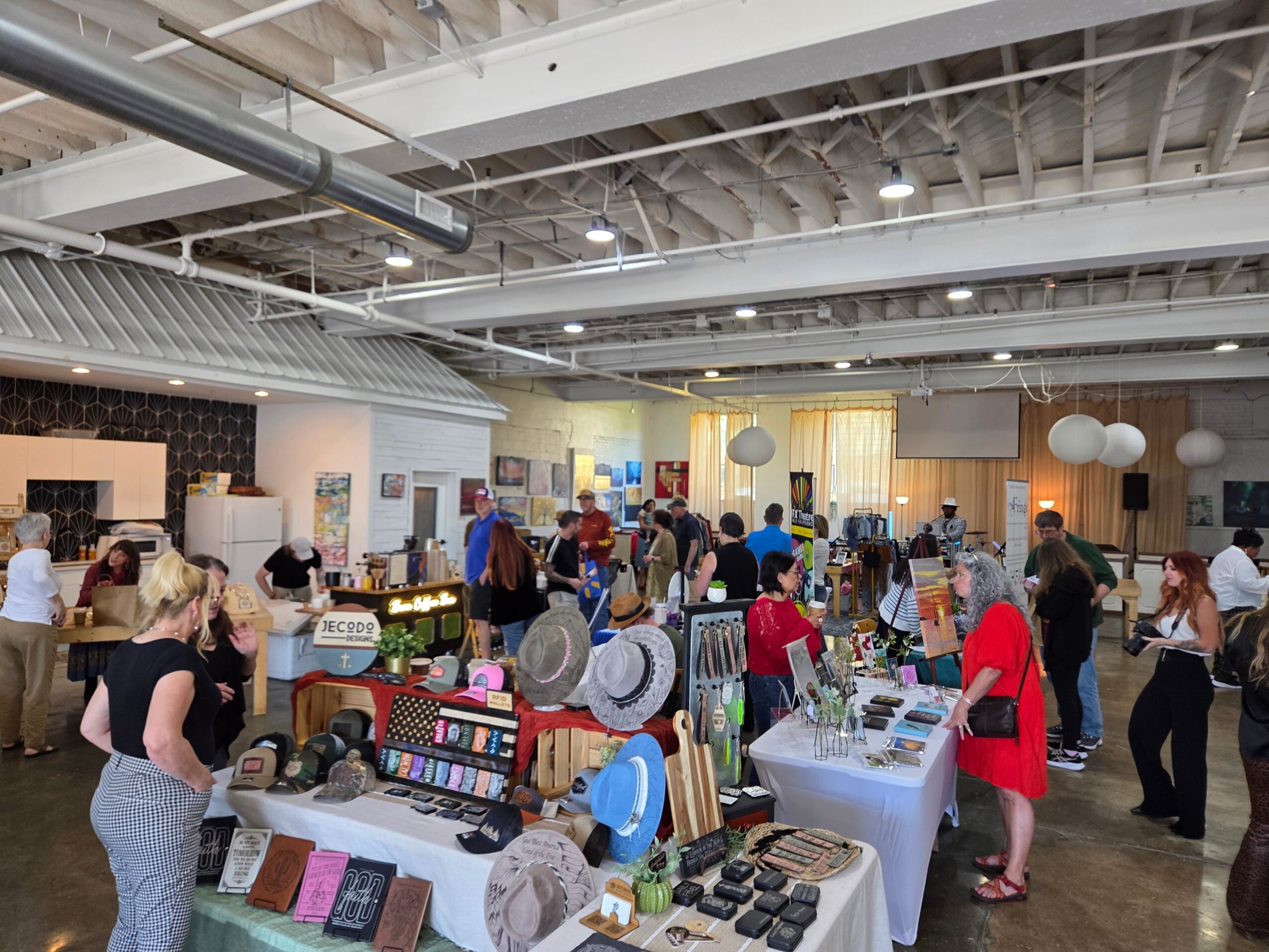 People browse vendor tables at an indoor market beneath exposed ceiling beams.