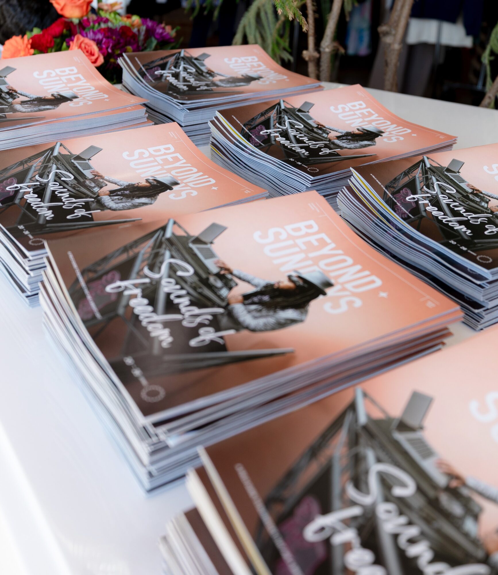Stacks of orange and black magazines arranged on a white table.