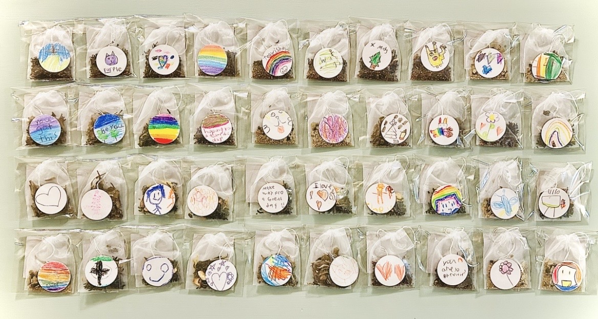 Four rows of individually wrapped circular decorated cookies arranged on a pale surface.