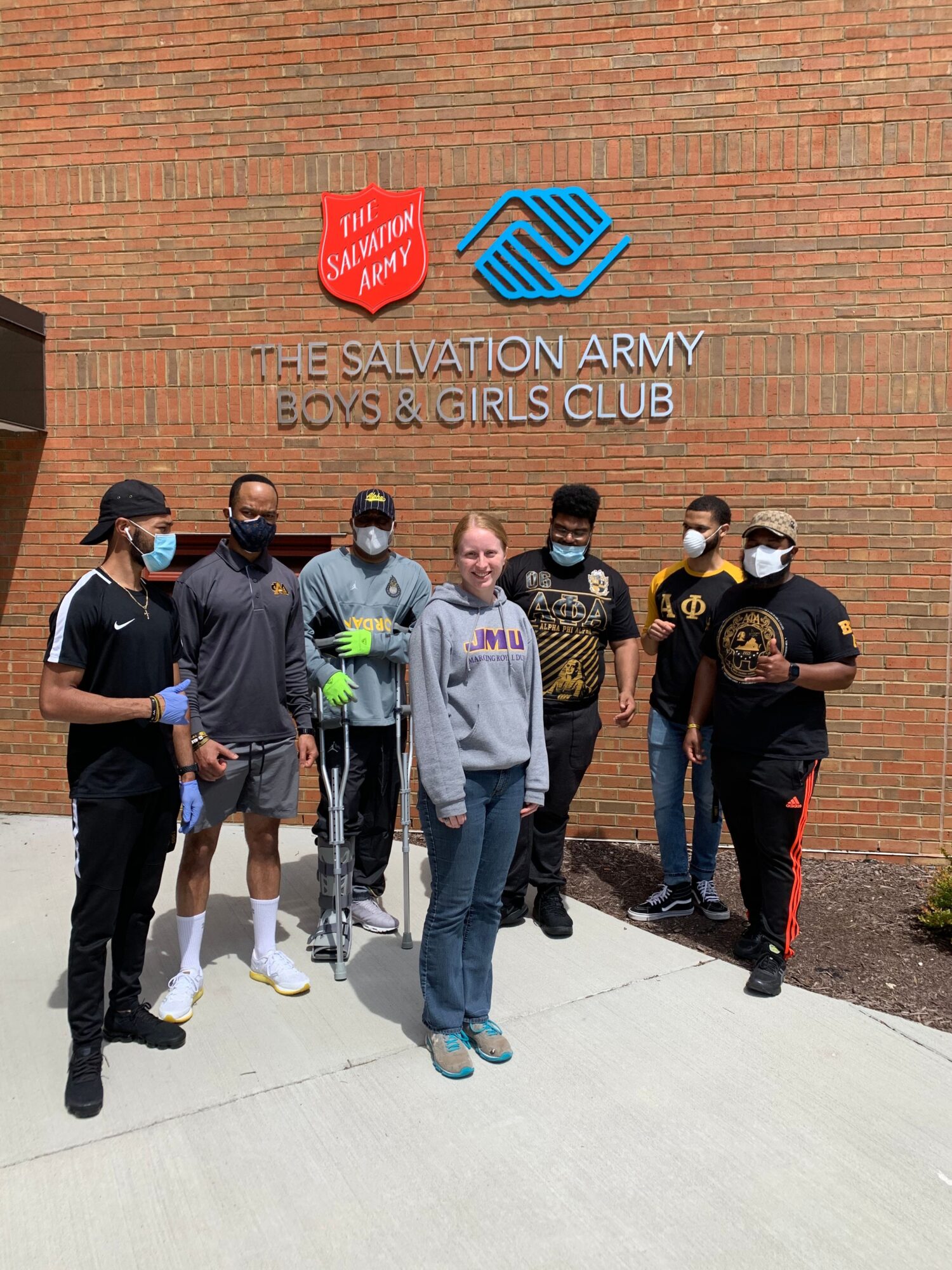 A group poses beside a brick wall with a Salvation Army Boys & Girls Club sign.