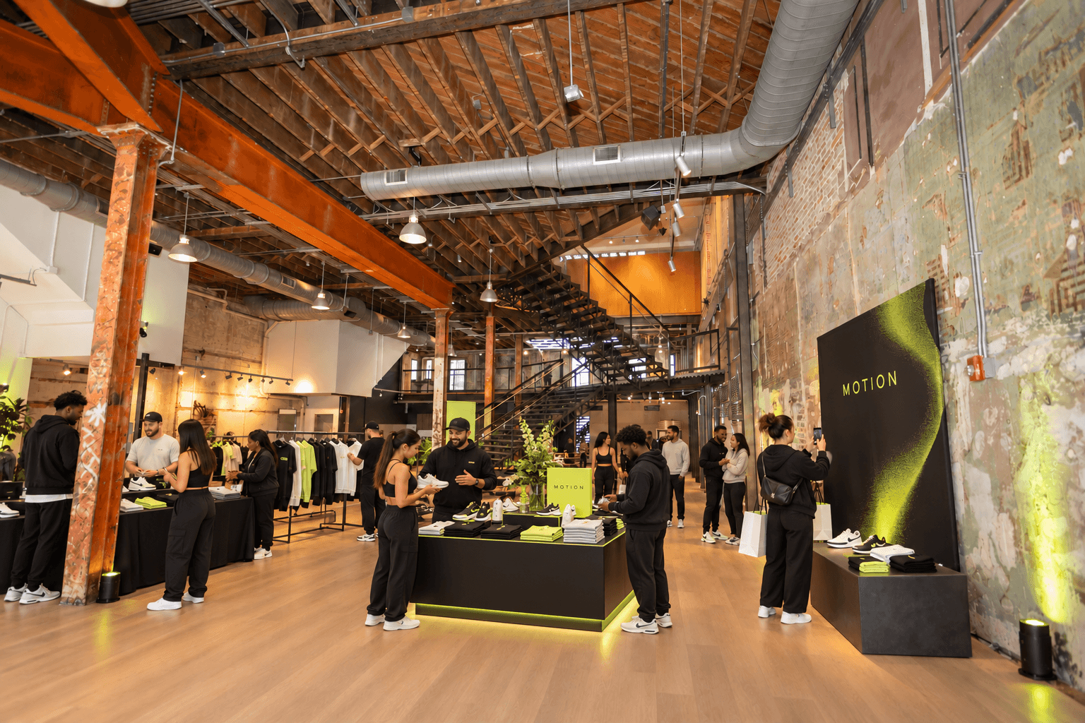 People browse clothing and displays inside a warehouse-style retail store with exposed beams and brick walls.