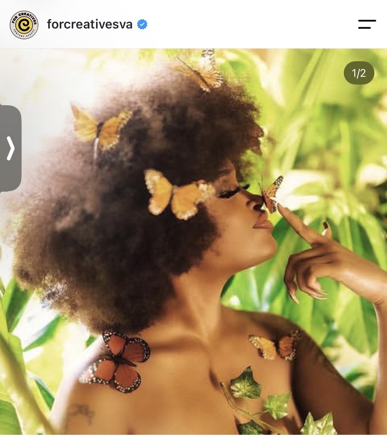 Person with butterflies on their hair and shoulder among green leaves.