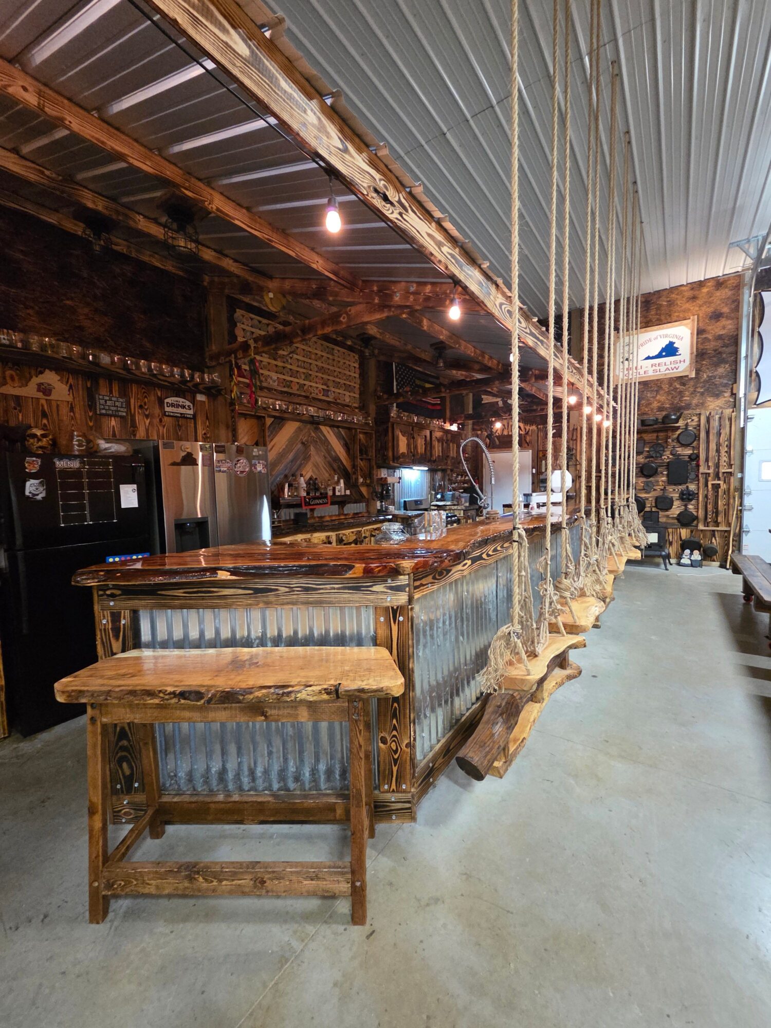Interior of a rustic wooden building with exposed beams, metal roofing, and a narrow walkway.