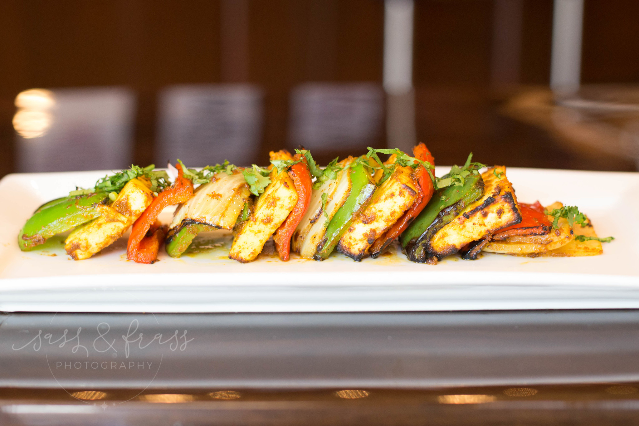 Grilled vegetable slices arranged in a row on a white rectangular plate.
