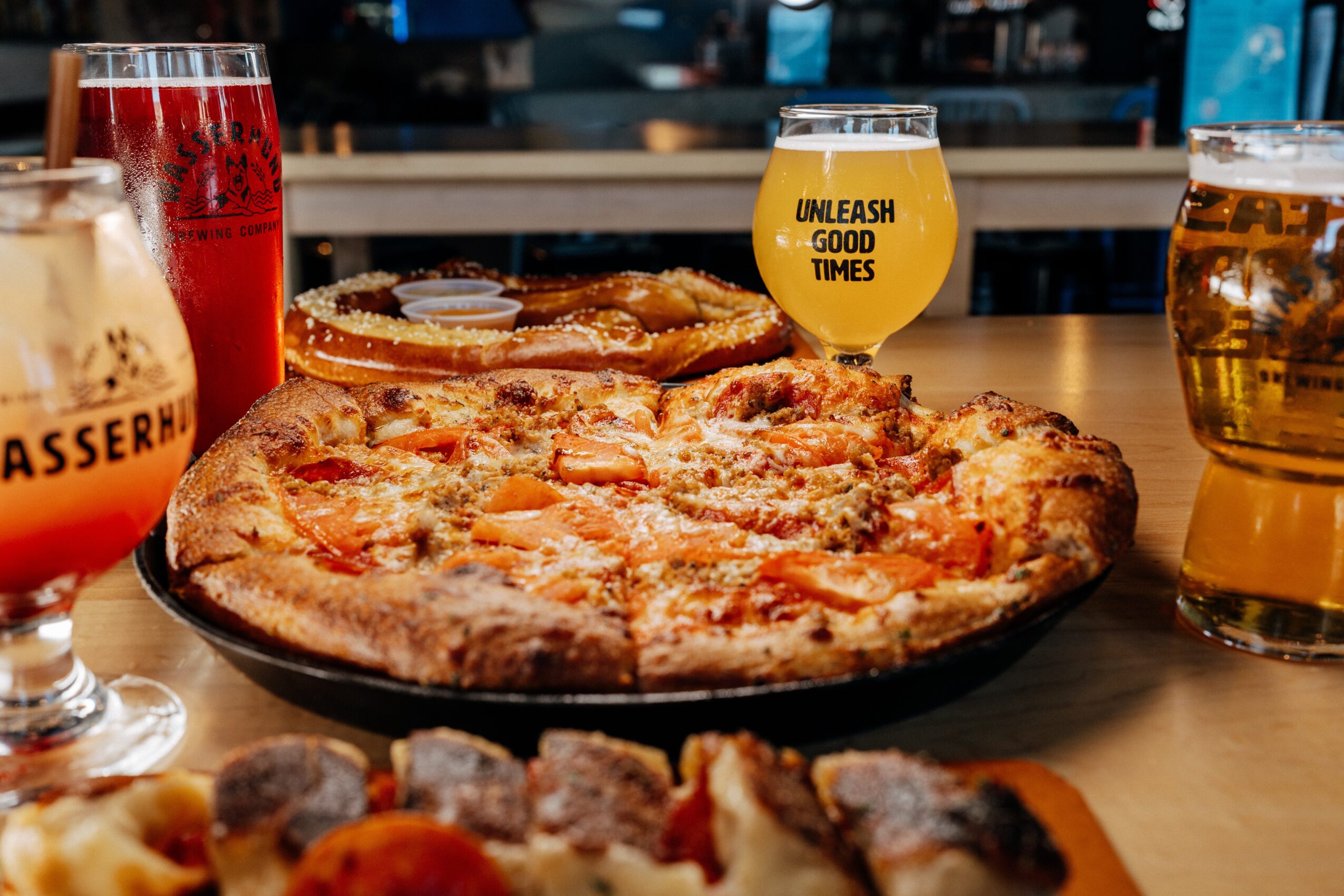 Several pizzas on a table with drinks in a restaurant.