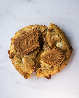 A round golden-brown cookie topped with two small rectangular chocolate biscuits on a pale surface.
